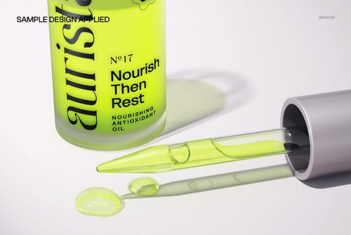 PSD mockup showing a silver pipette and green serum drops beside a green bottle, highlighting cosmetic product details.