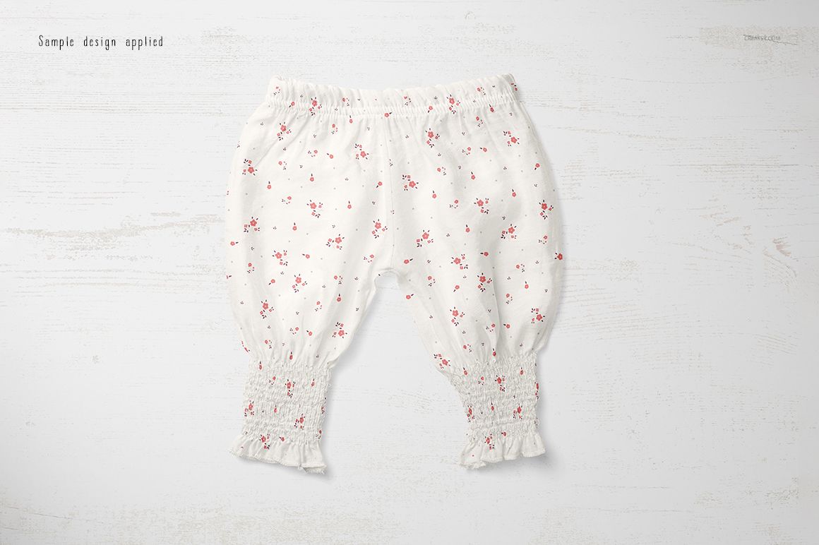 Baby summer pants mockup featuring a white fabric with tiny red flowers, shown flat on a textured white background.