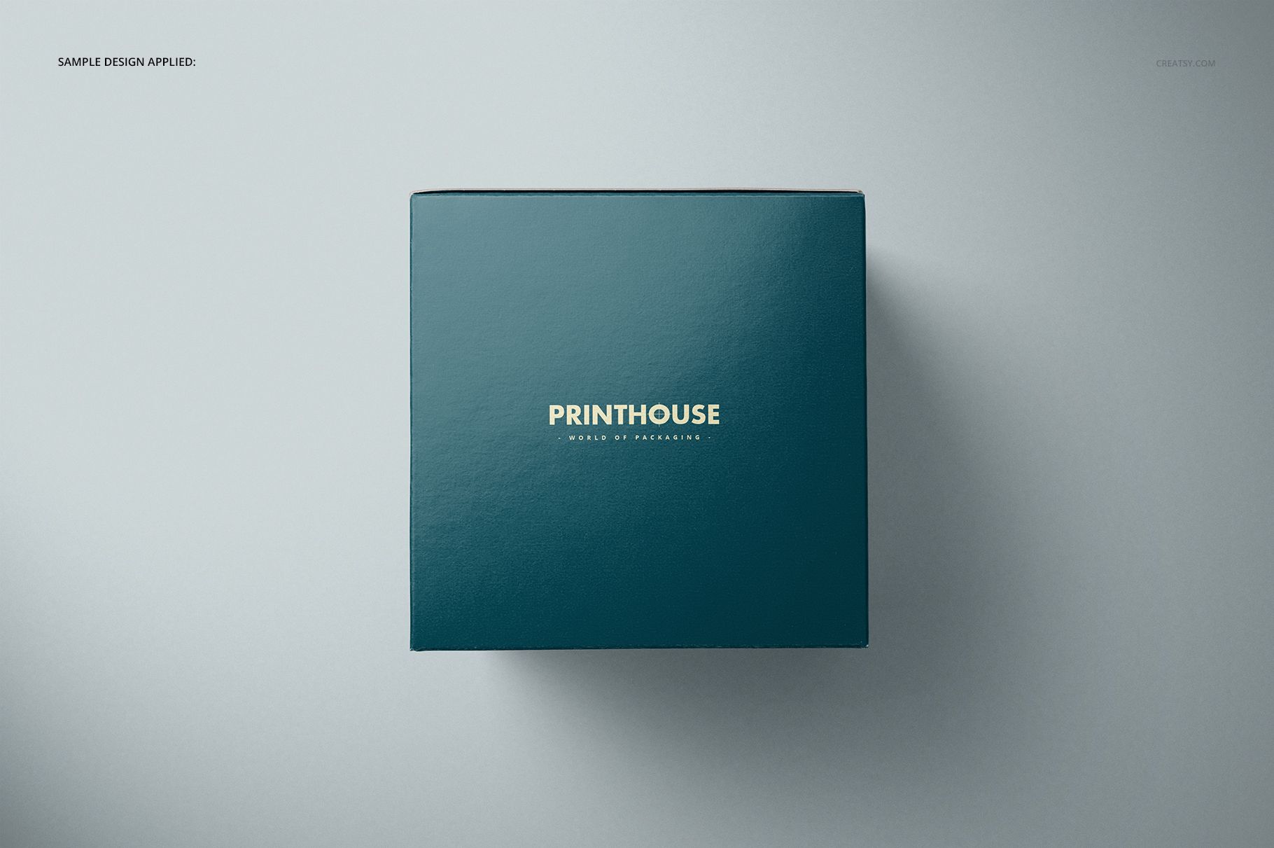 Square gift box mockup featuring a glossy teal surface and centered gold lettering, viewed from above.