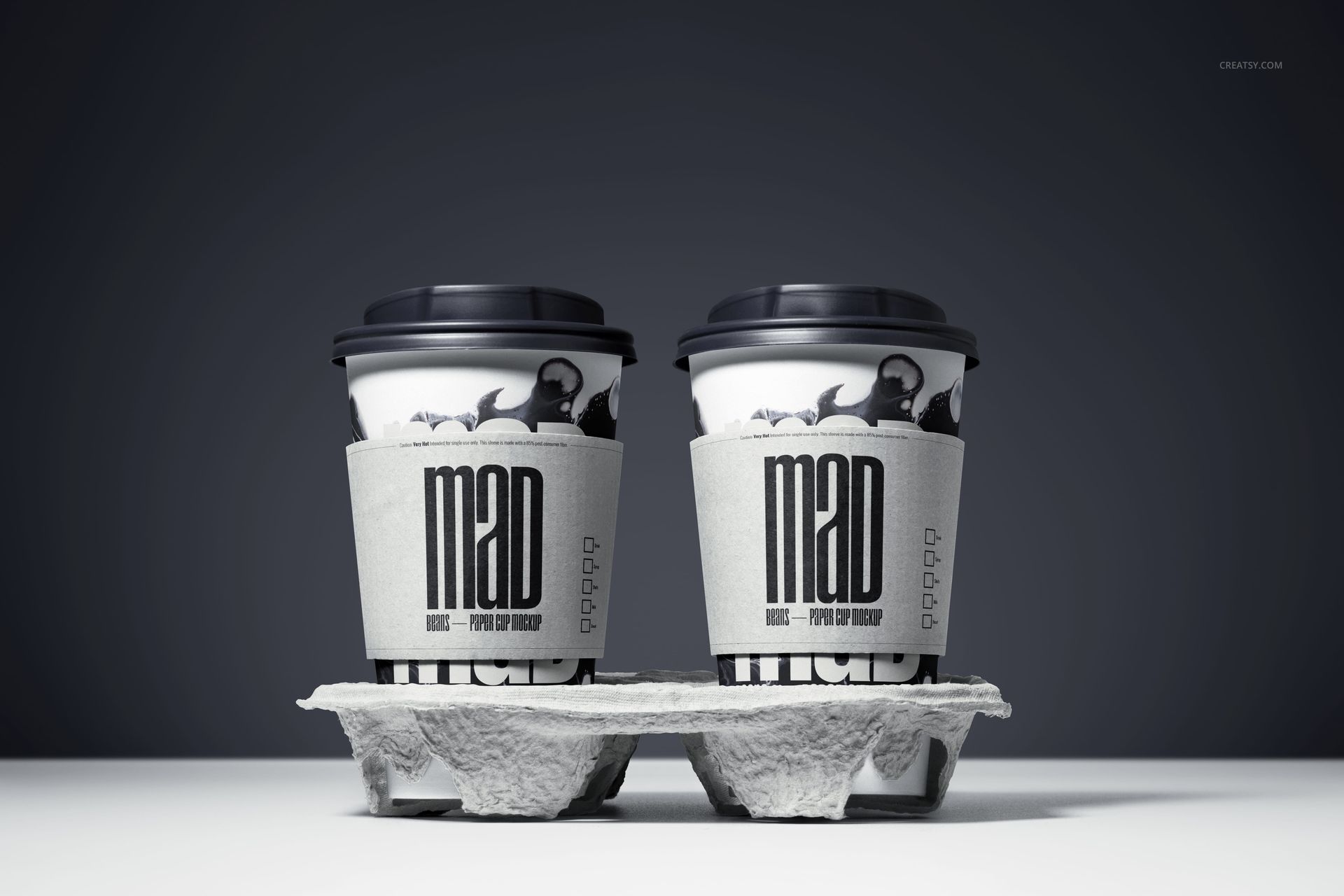 PSD mockup featuring a pair of paper cups with black lids and custom sleeves, displayed in a drink tray under studio lighting.