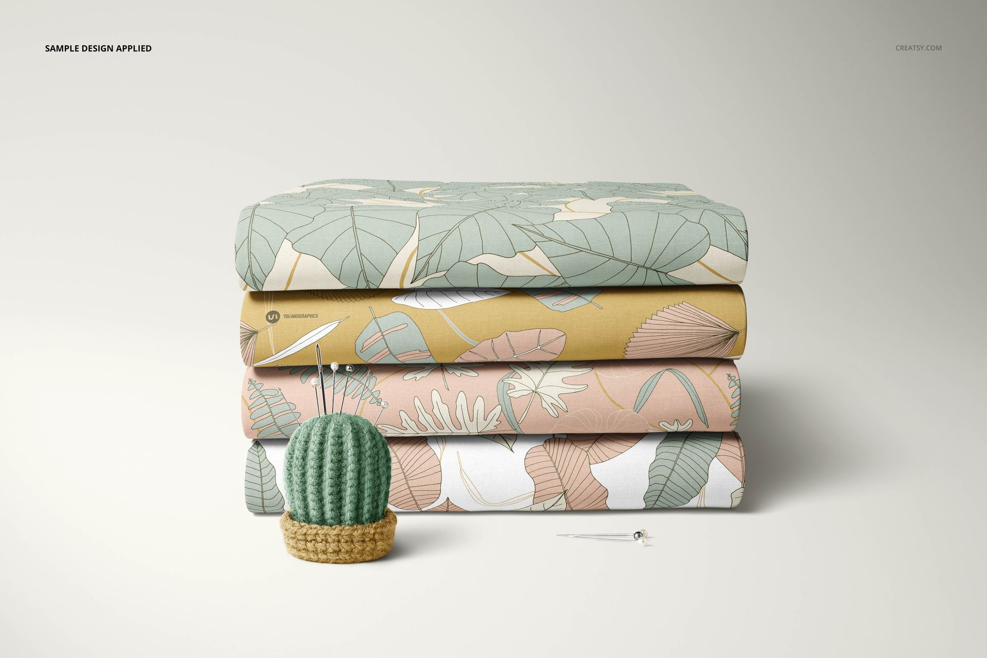 Fabric stack mockup featuring three folded textiles with leaf and floral designs, shown from the front on a plain background.