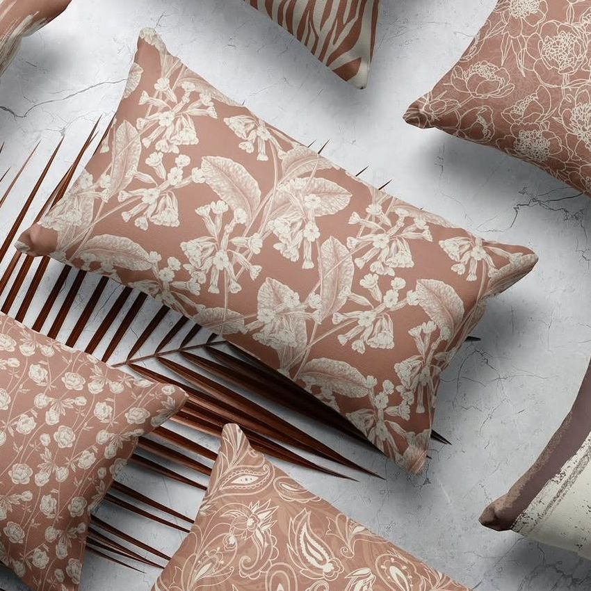 Rectangular pillow mockup featuring multiple pillows with beige botanical and floral patterns on brown backgrounds, arranged on a marble surface.
