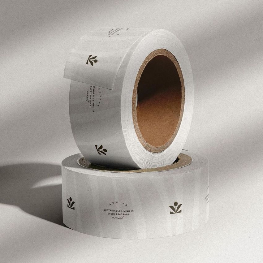 Packing tape mockup showing two rolls of white tape with minimal black graphics and text, placed on a neutral surface.