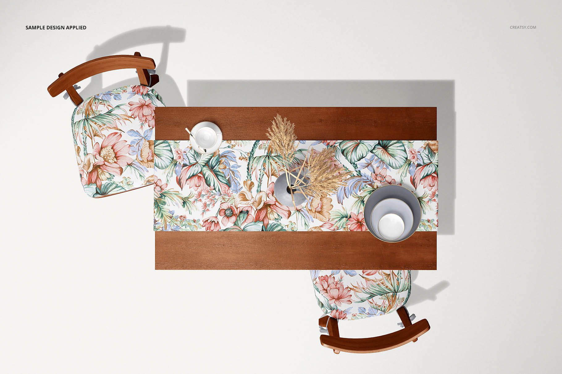 Overhead perspective of a wooden table featuring a colorful table runner mockup, two chairs, and decorative props.