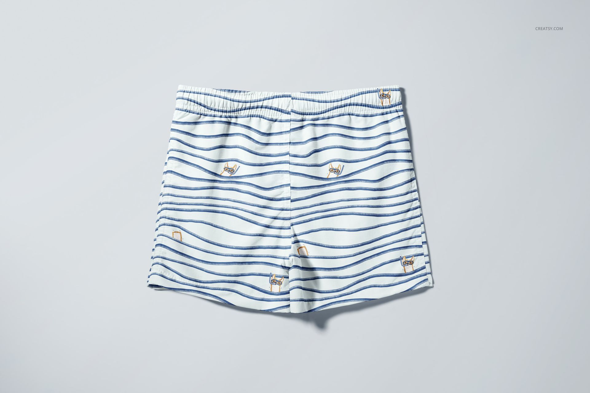 Front view of kids swim shorts mockup featuring blue wave patterns and playful animal motifs on white fabric.