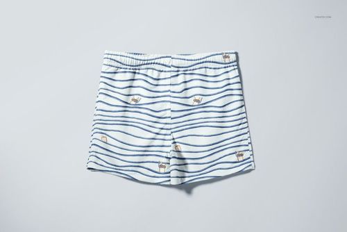 Front view of kids swim shorts mockup featuring blue wave patterns and playful animal motifs on white fabric.