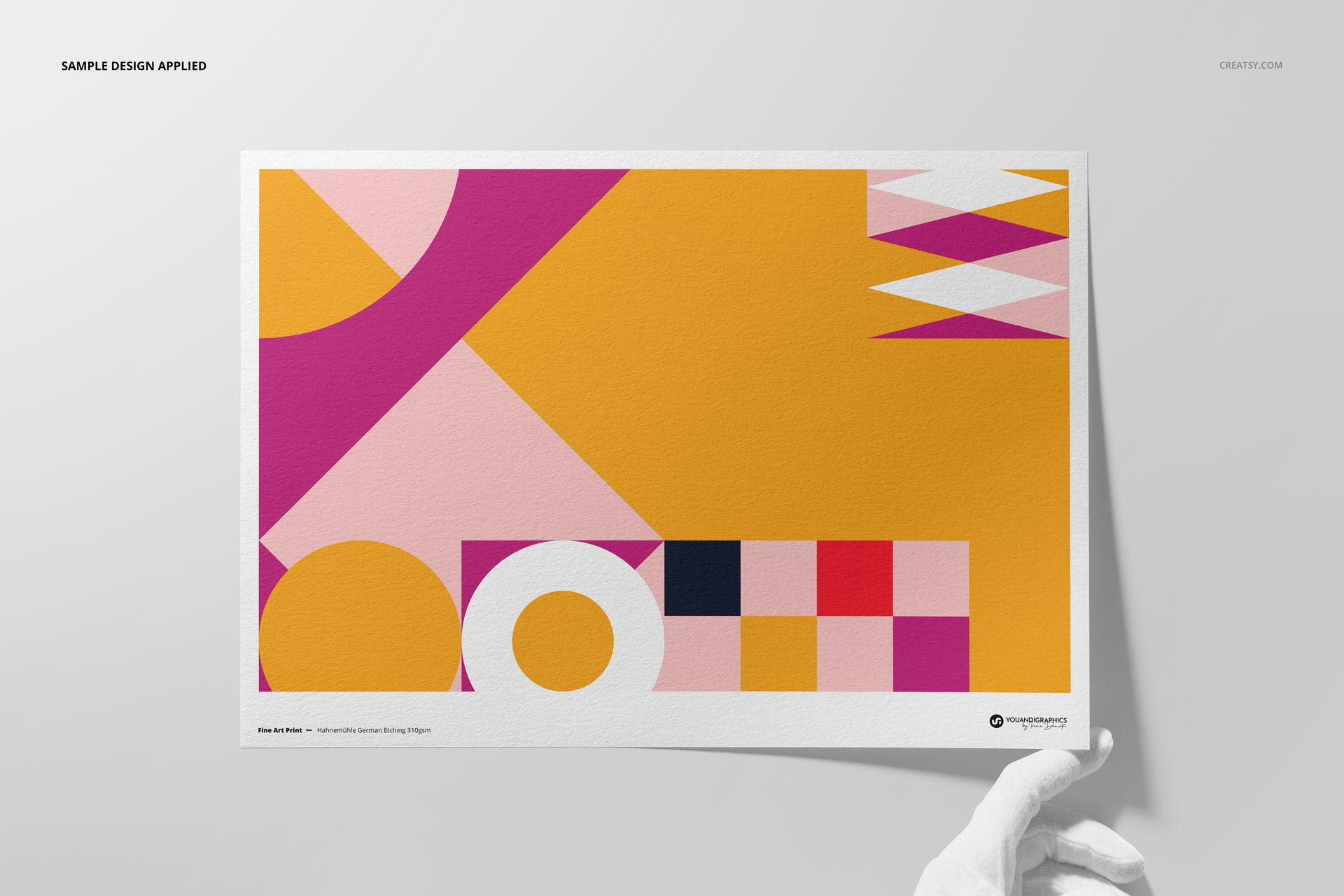 A3 fine art print mockup held by a gloved hand, featuring a bold geometric pattern in pink, yellow, and white.