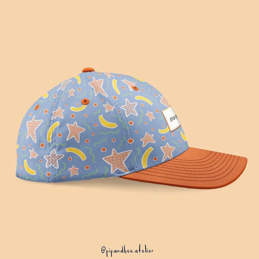 Fullcap mockup featuring a blue cap with colorful star, banana, and swirl patterns, orange brim, and a small label on the side.
