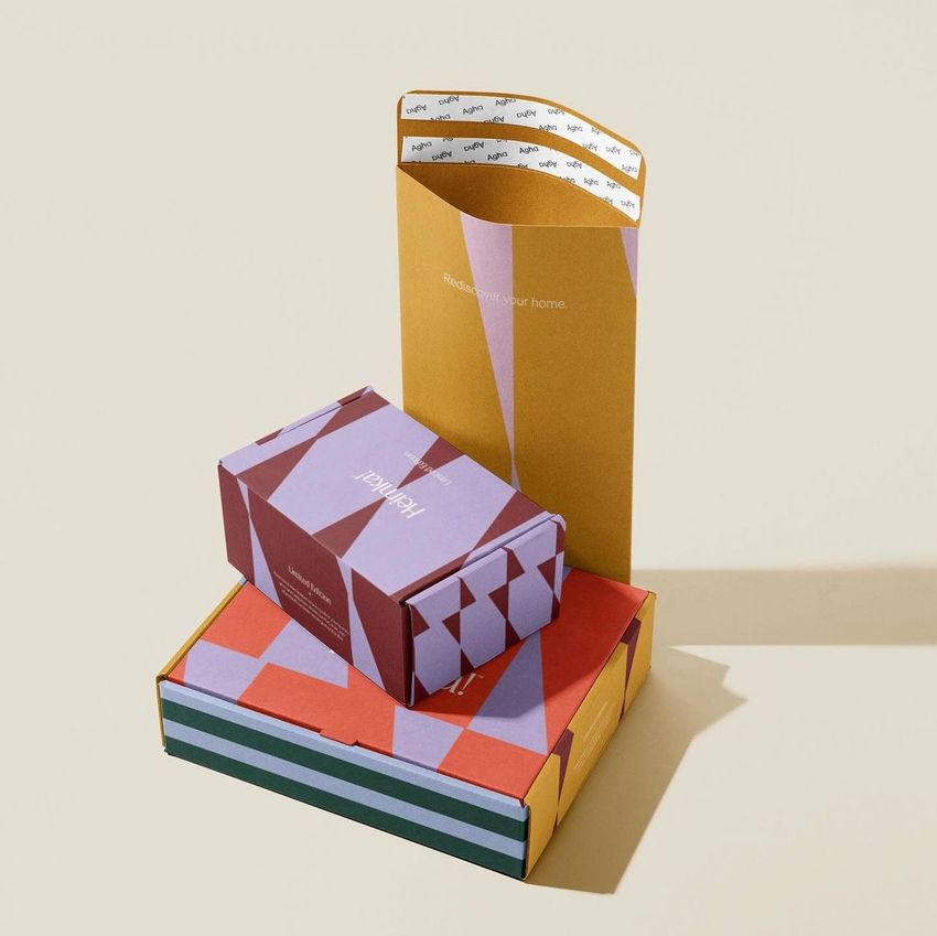 Packaging mockup set featuring three colorful mailer boxes with geometric patterns arranged on a neutral beige surface.