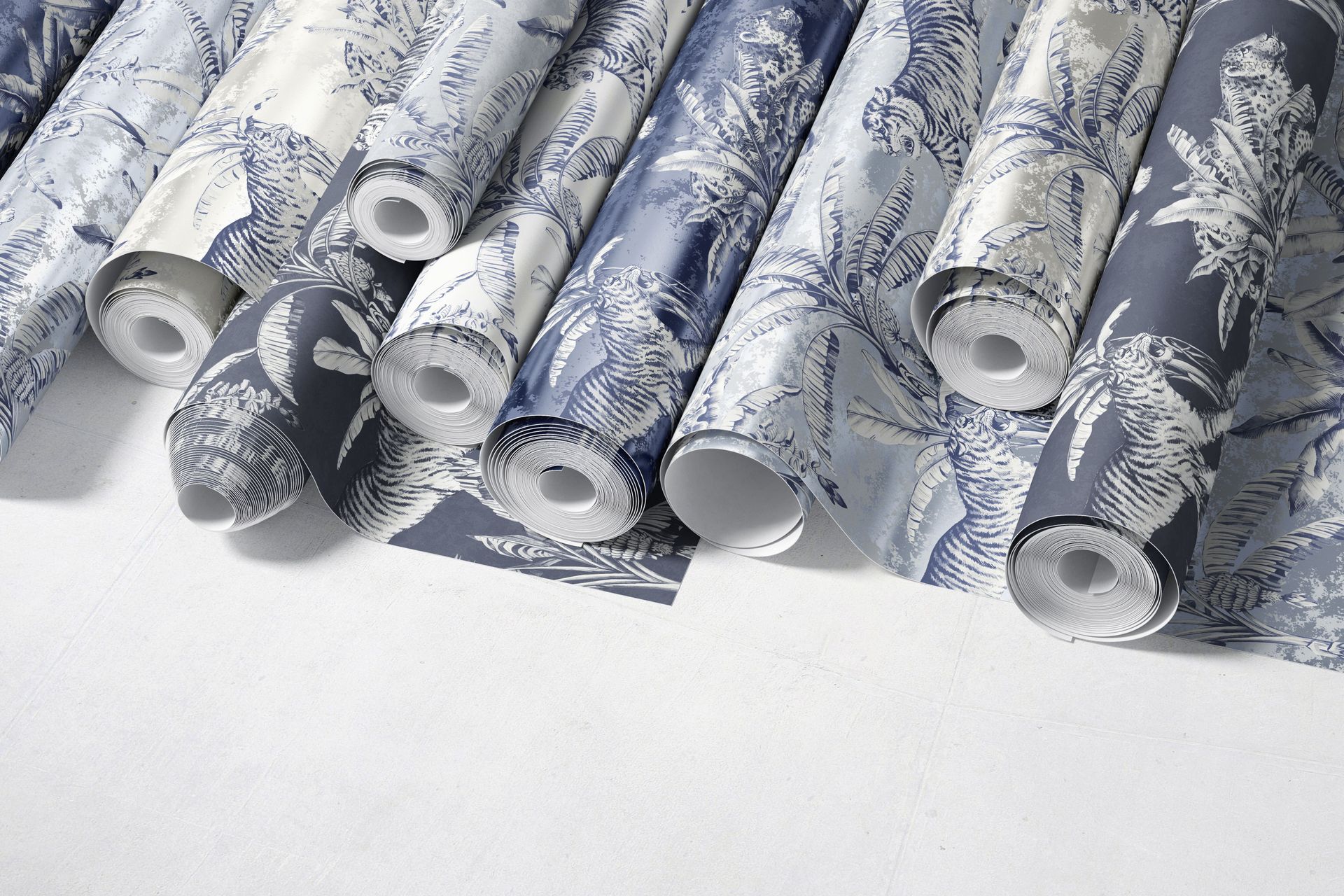 Paper wallpaper mockup showing several patterned rolls with botanical and animal motifs, photographed from above.