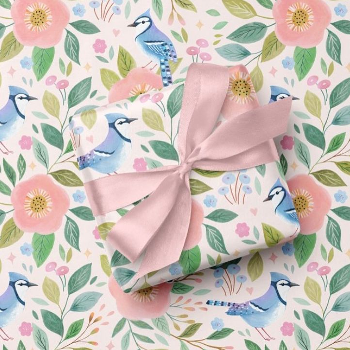 Square gift box mockup wrapped in paper with blue birds, pink flowers, and green leaves, tied with a pale pink ribbon.