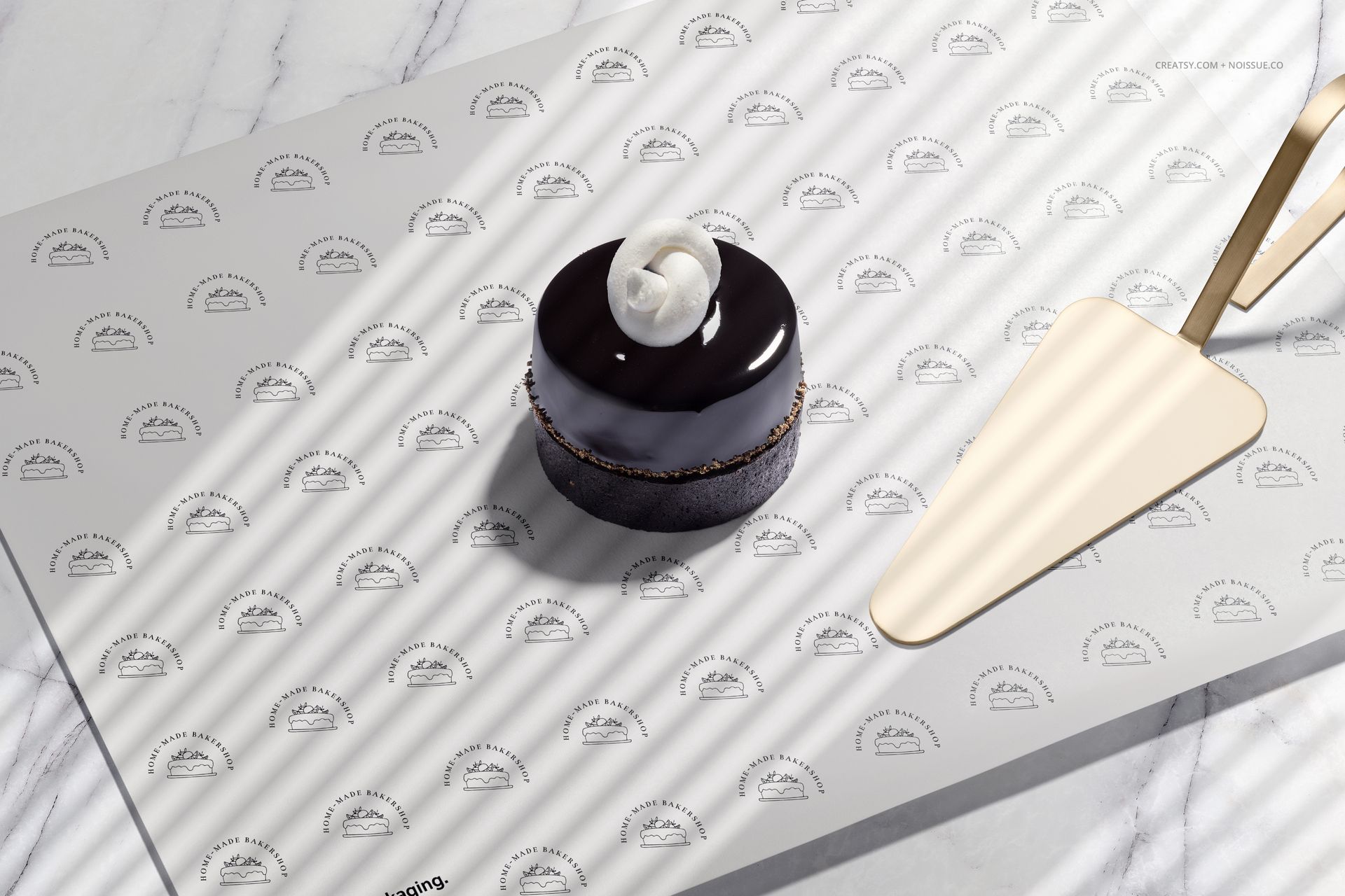 PSD mockup scene showing a small pastry on branded food safe paper, marble countertop, and a gold cake server.