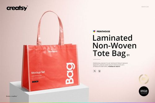 Front view of a red laminated non-woven tote bag mockup with white text, displayed on a light surface against a pale pink background.