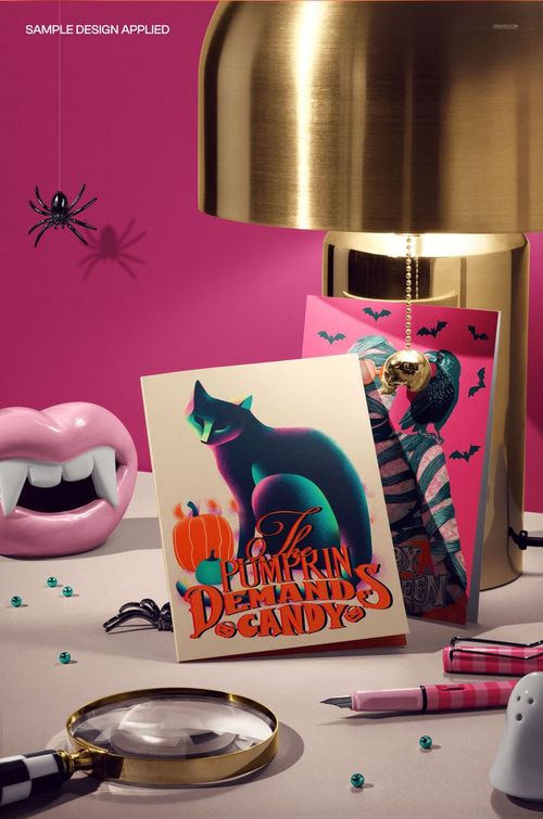 Halloween PSD mockup showing greeting cards, vampire teeth, magnifying glass, pens, and decorative spiders on a desk.