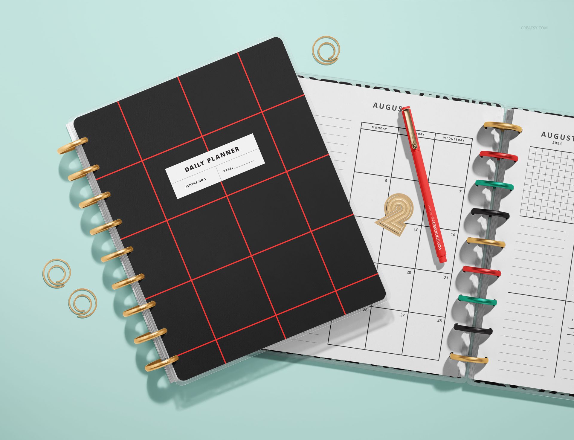 Top view of a spiral planner mockup with grid-patterned cover, open to divider pages with calendar and pen.