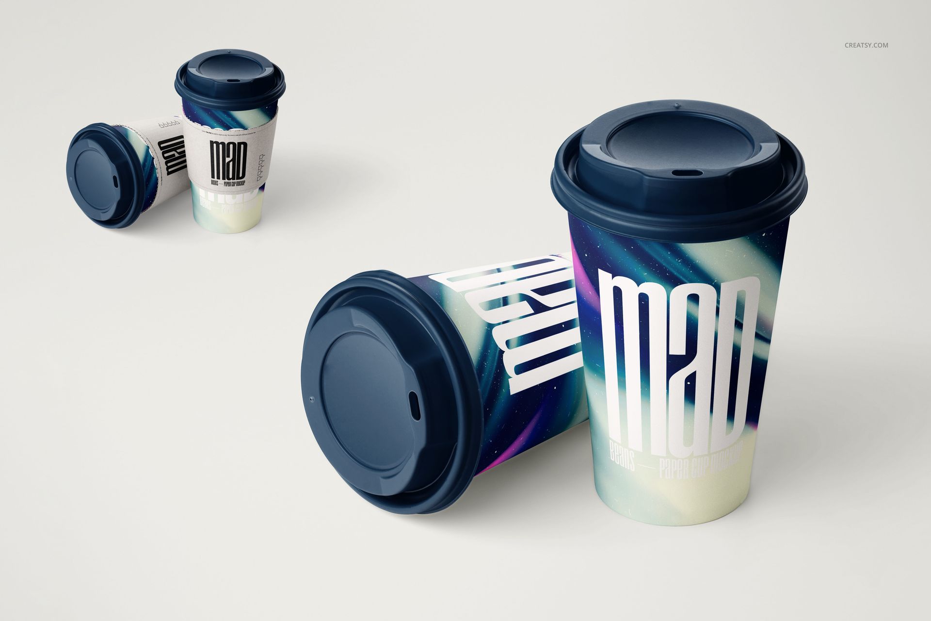 Paper coffee cup PSD mockup set showing two cups with removable sleeves, dark lids, and colorful abstract patterns.