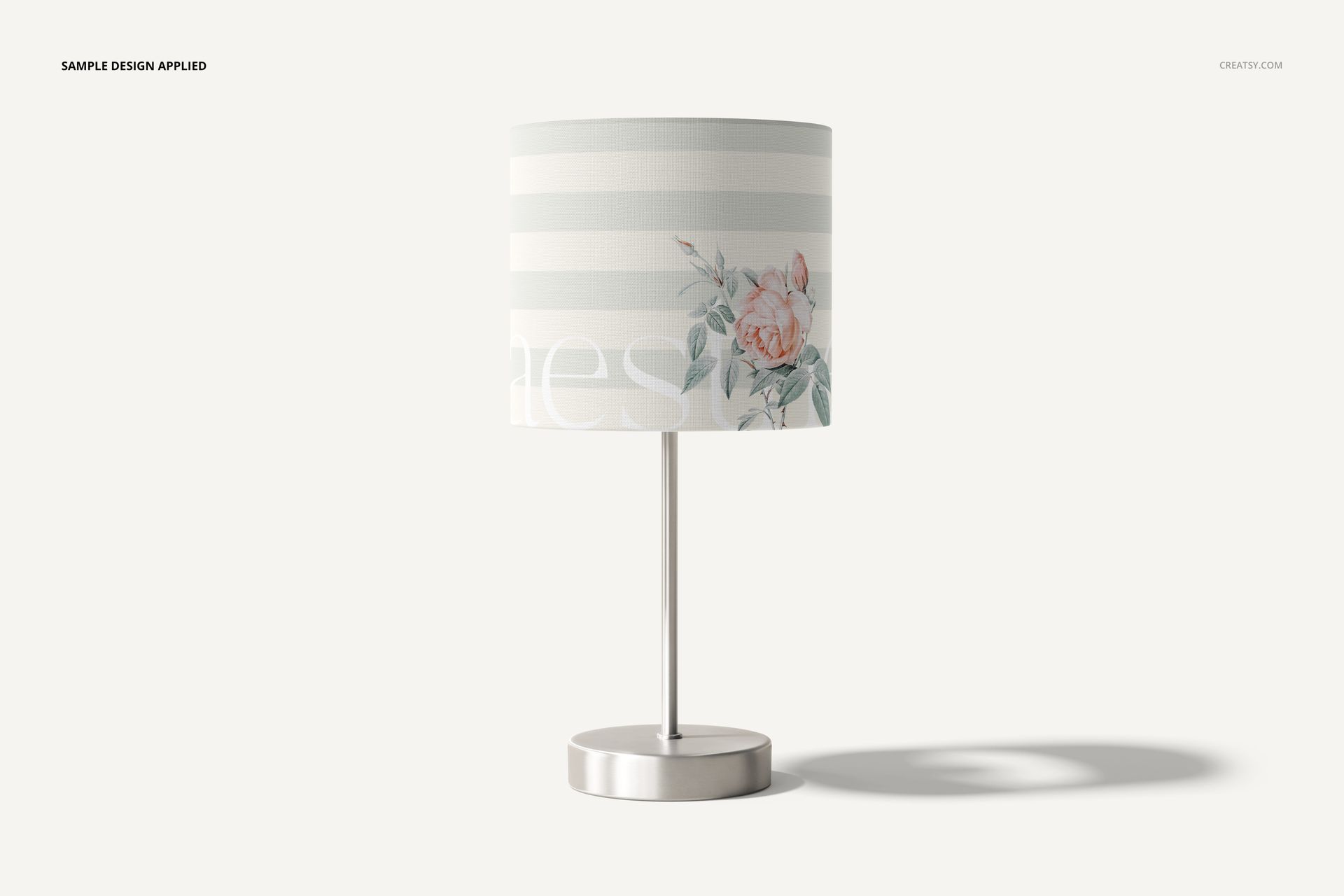 Lamp shade mockup with a cylindrical shape, featuring soft horizontal stripes and a floral design, shown on a metal stand.