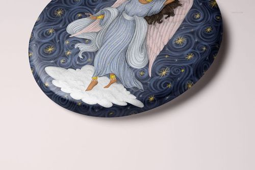Oval-shaped Christmas ornament mockup featuring an angel illustration with blue and pink tones on a cloud background.