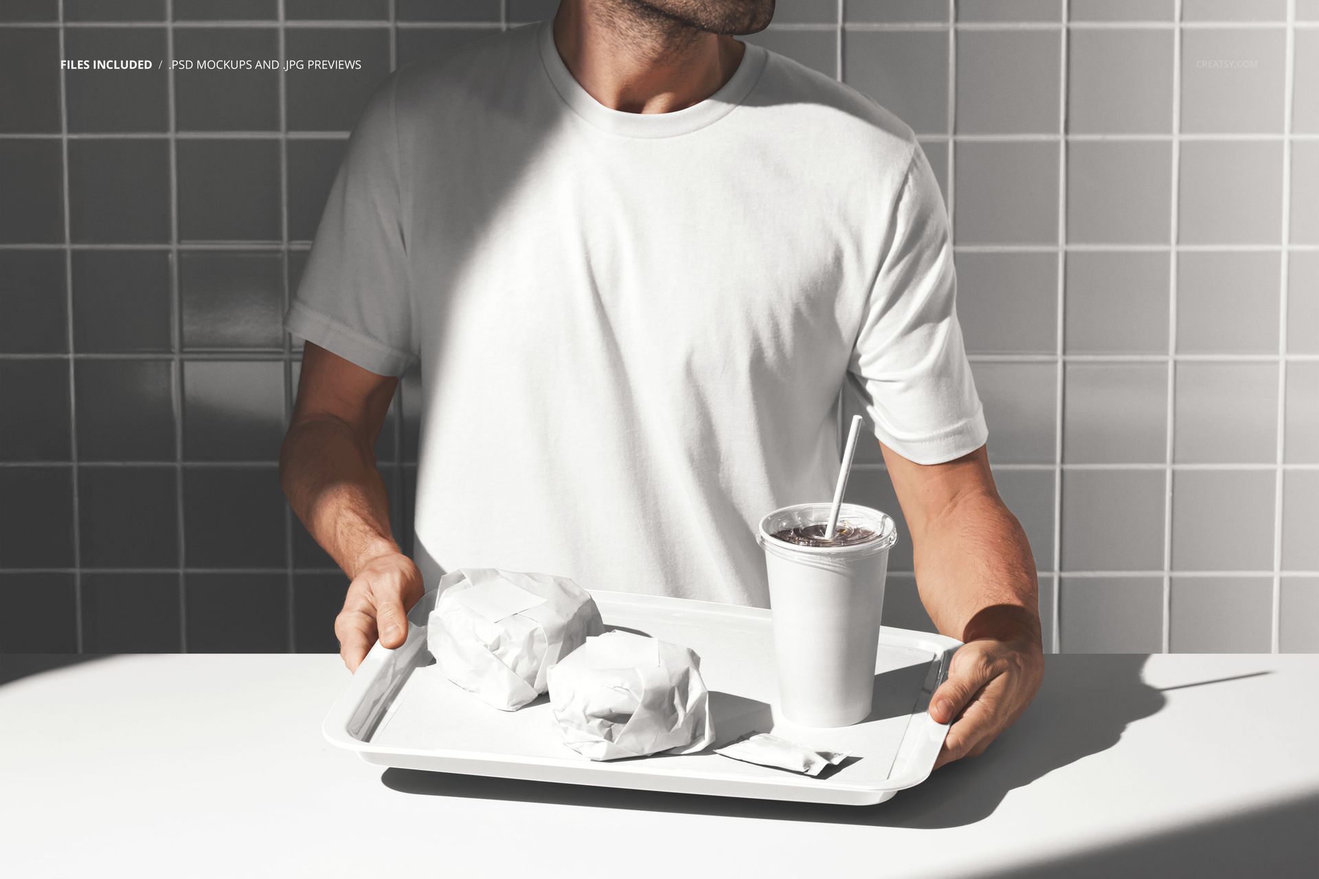 PSD mockup showing a man presenting a tray with wrapped burgers, a disposable drink cup, and condiment sachet.