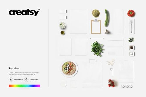 Top view of Greek restaurant table mockup with various blank items, vegetables, herbs, and a plate of food on white background.