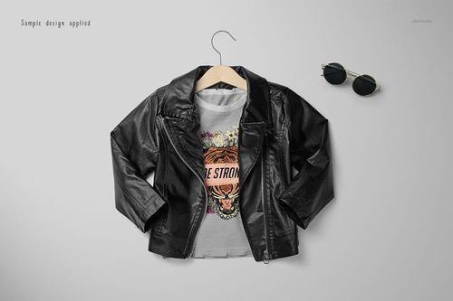 Front view of a girls chic set mockup featuring a black faux leather jacket on a hanger over a graphic t-shirt, with sunglasses nearby.