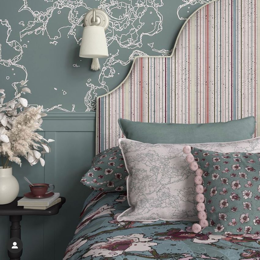 Bedroom pillows, a striped headboard, and floral wallpaper mockup with muted green and pink tones, viewed from the side.