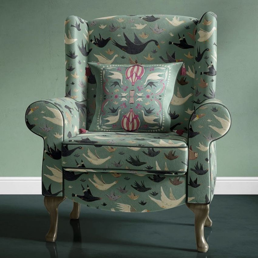 Retro velvet armchair mockup featuring a green armchair with a bird pattern and matching decorative pillow in a minimalist room.