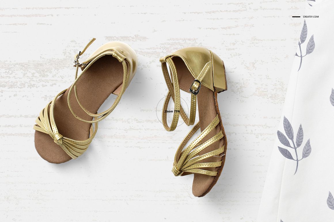 Top view of a baby summer set mockup featuring gold sandals on a light wooden surface with a patterned fabric.