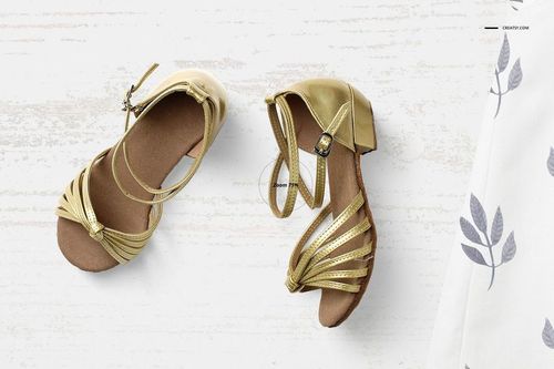 Top view of a baby summer set mockup featuring gold sandals on a light wooden surface with a patterned fabric.