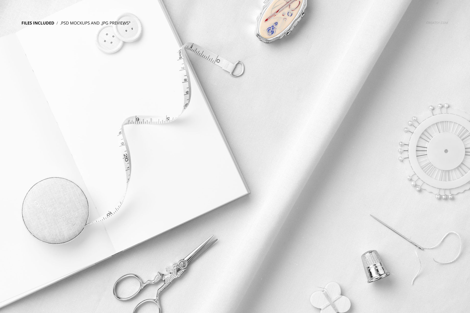 Top view of cotton fabric mockup with sketchbook, sewing tools, buttons, and measuring tape on a light surface.