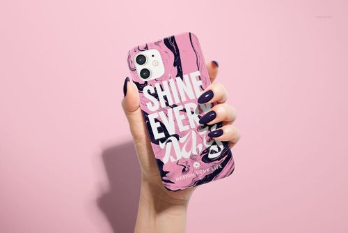 PSD mockup of an iPhone 12 snap case with bold text and swirling pink-black pattern, shown from the back in a hand.