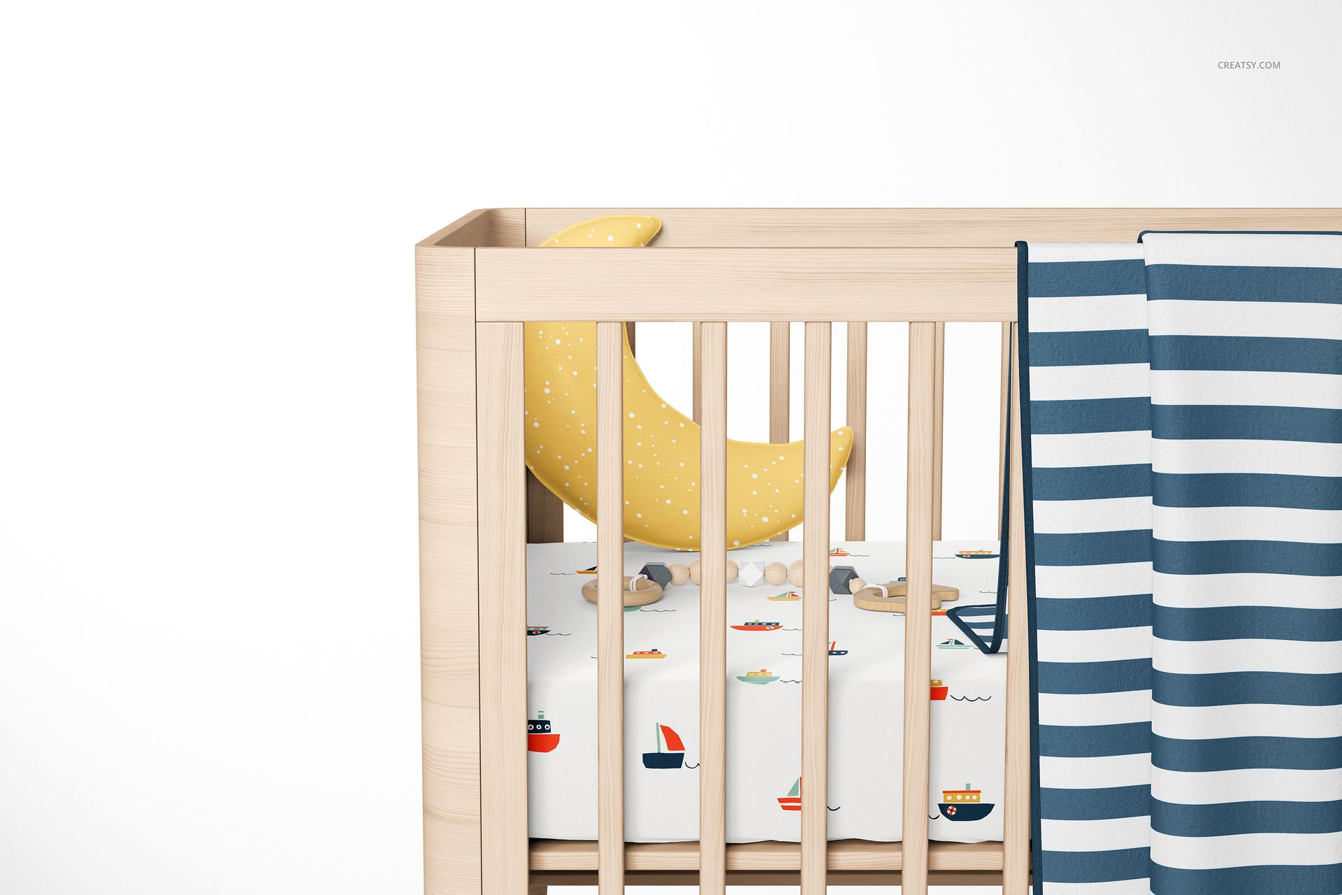PSD mockup of a baby crib with a fitted sheet decorated with boats, striped blue and white blanket, and moon pillow.