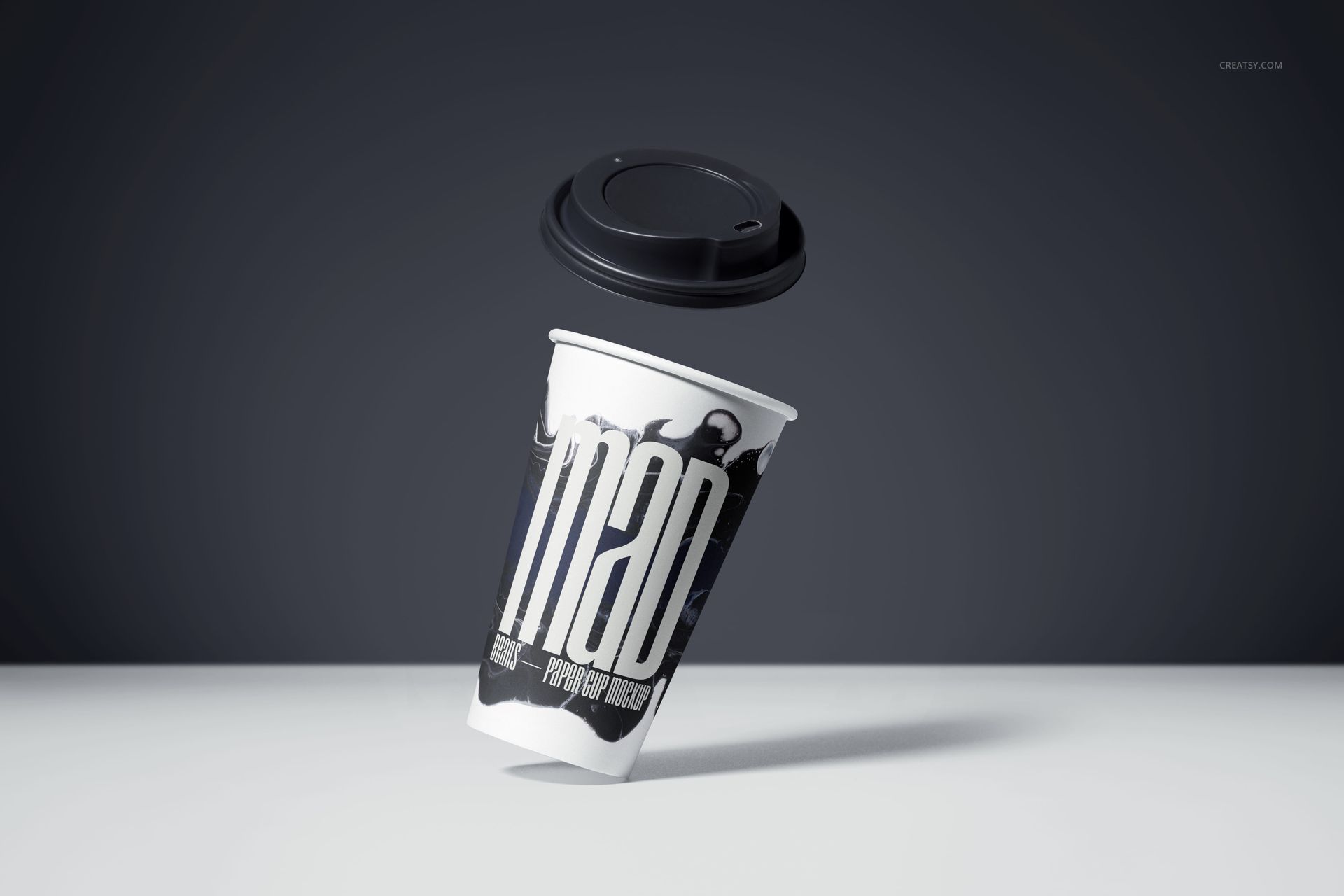 PSD mockup of a paper drinkware cup with modern monochrome artwork, lid hovering above, set against a minimalist gray backdrop.