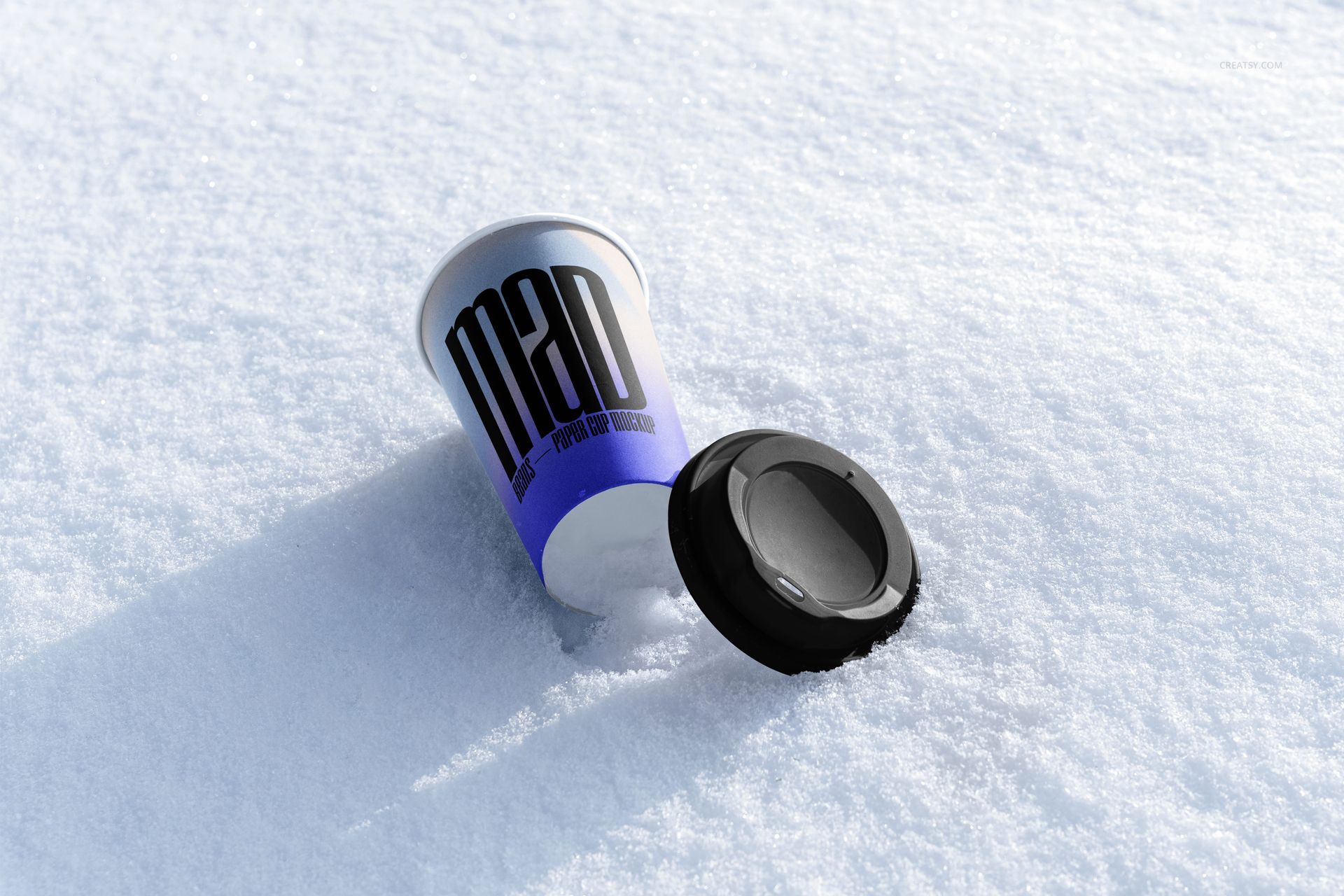 Winter-themed paper cup mockup with bold black text, cup and lid resting on snowy surface, angled perspective.