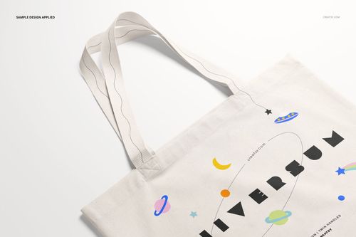 Weekender tote bag mockup shown from an angle, decorated with colorful planets and stars on a cream fabric.