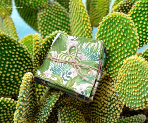 PSD mockup showing a bundle of patterned fabric with floral and leaf designs resting on spiky cactus pads.