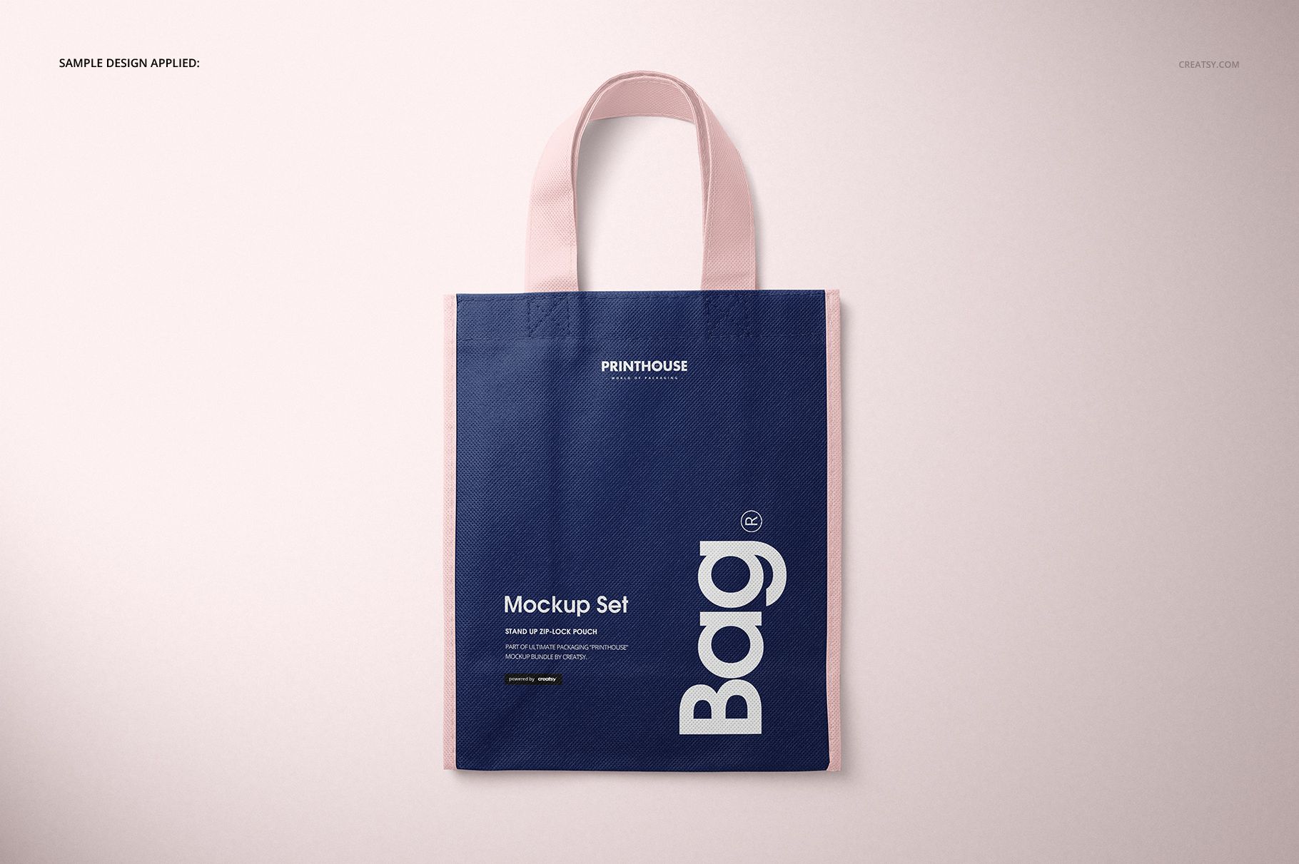 Non-woven tote bag PSD mockup featuring a rectangular shape, dark blue front panel, and pastel pink handles.