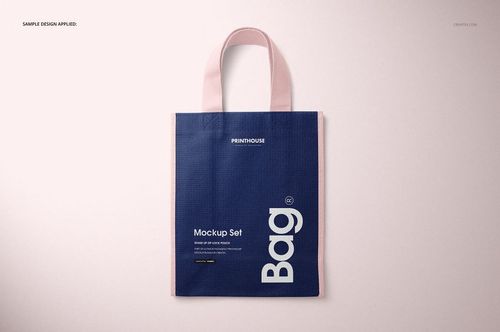 Non-woven tote bag PSD mockup featuring a rectangular shape, dark blue front panel, and pastel pink handles.
