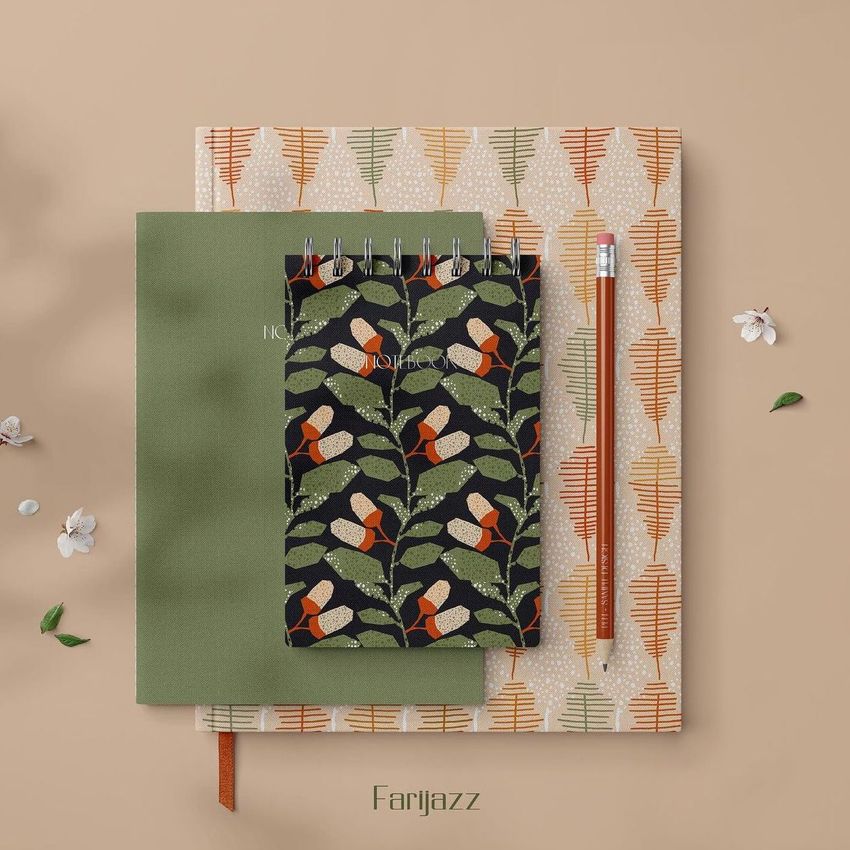 Stationery mockup featuring a spiral notebook with a leaf and bird pattern, a green hardcover book, and a pencil on a beige background.