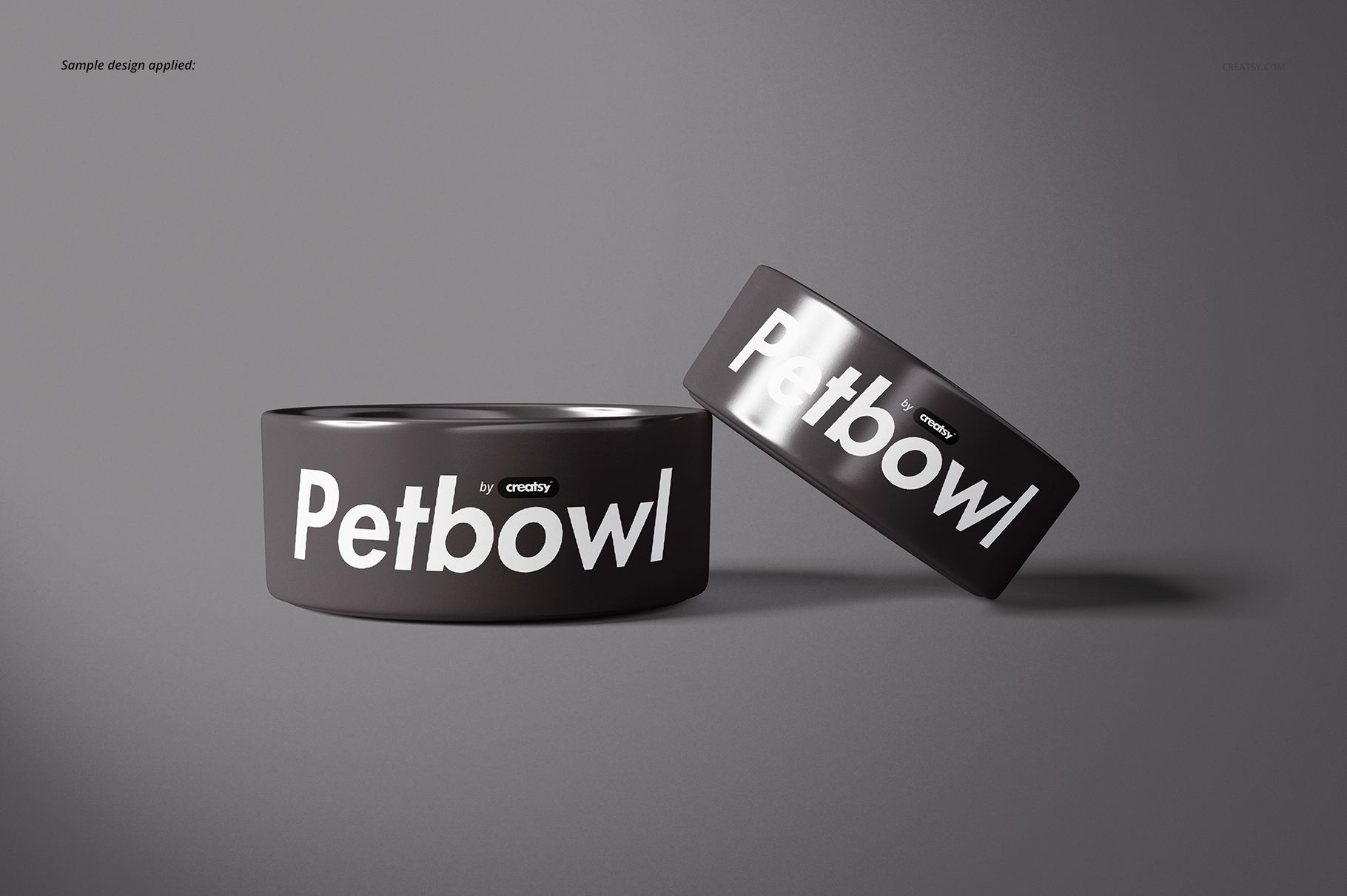 PSD mockup showing two ceramic pet bowls in black with white text, one upright and one tilted on a gray backdrop.