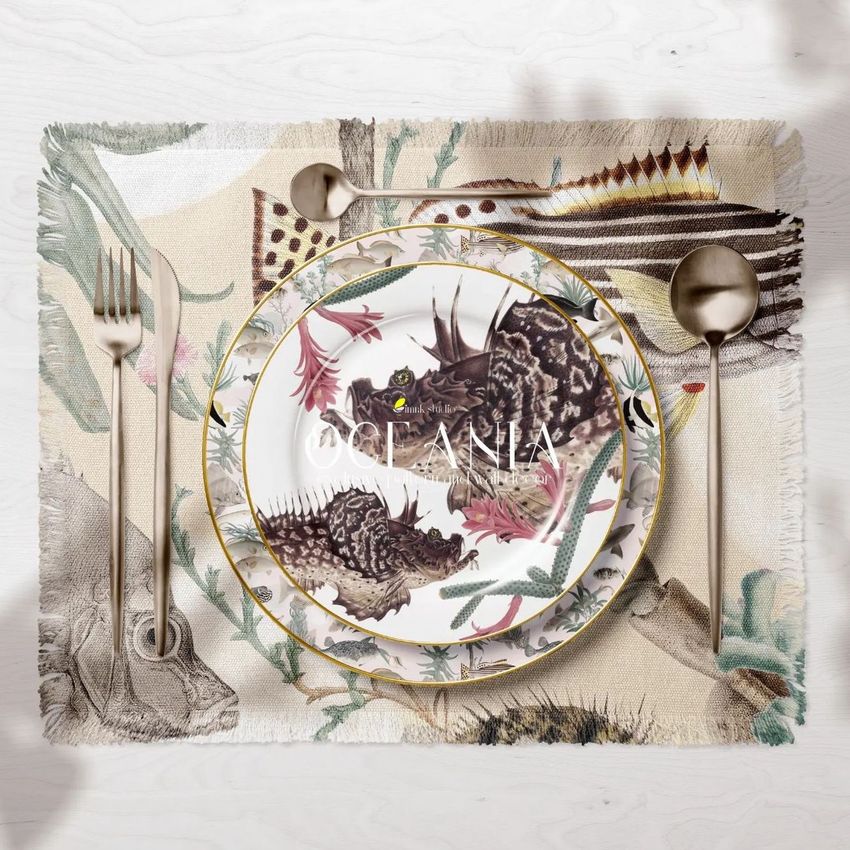 Fringed placemat and decorative plates mockup featuring botanical and animal illustrations, with gold cutlery on a light wood surface.