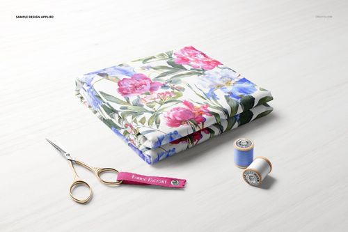 Folded fabric mockup featuring vibrant pink and blue flowers, shown from a top angle with sewing tools beside it.