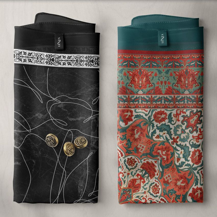 Three folded silk scarves mockup showing two scarves with distinct patterns, one in black and white with gold accents, and one in red, teal, and beige with ornate designs, placed on a light surface.