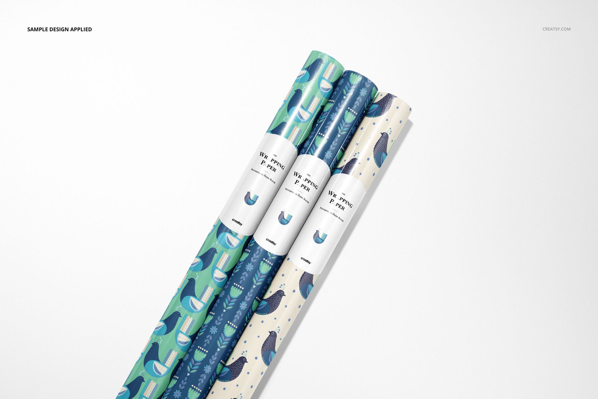 PSD mockup featuring three decorative wrapping paper rolls with assorted designs, placed on a light backdrop.