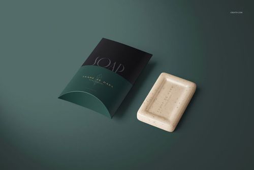 Hotel hand soap bar and pillow-shaped packaging mockup set on a dark green background, seen from above.
