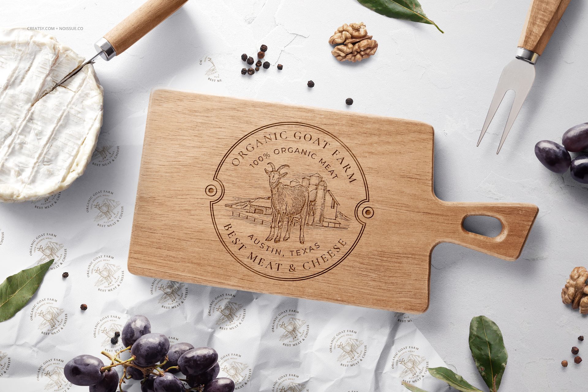 Top view of a wooden board mockup with engraved design, cheese wrapping paper, grapes, leaves, and cheese wedge.