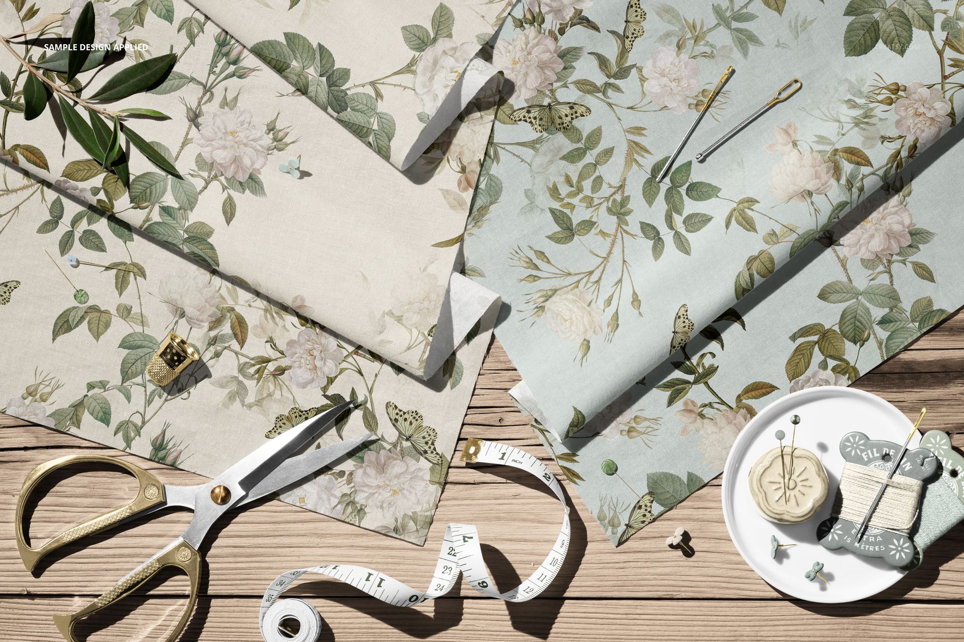 PSD mockup showing floral cotton fabrics with butterflies, sewing accessories, and a plate of buttons in a flat lay.