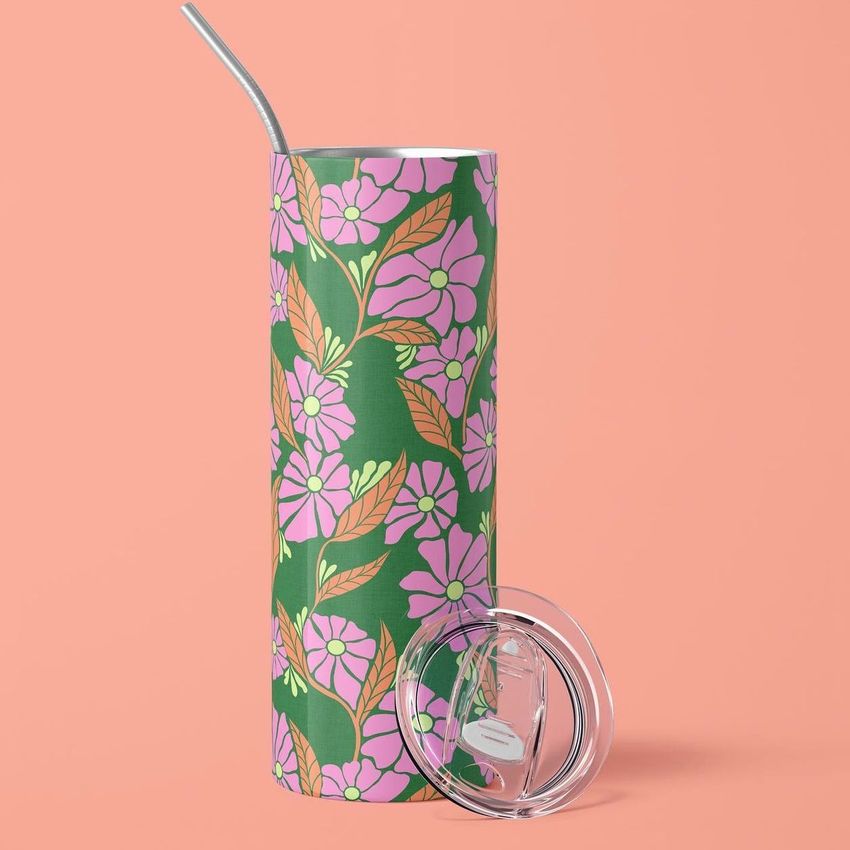 20oz skinny tumbler mockup featuring a vibrant pink and green floral pattern, with a metal straw and clear lid on a peach background.