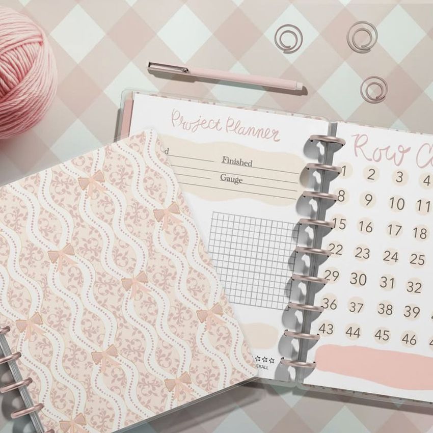 Top view of two spiral planners on a pastel checkered surface, one open showing planner pages and one closed with a lace pattern cover.