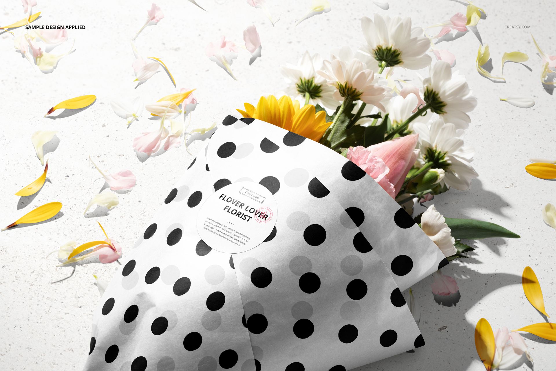 PSD mockup featuring floral packaging with a black dot pattern, flowers and scattered petals displayed on a white background.